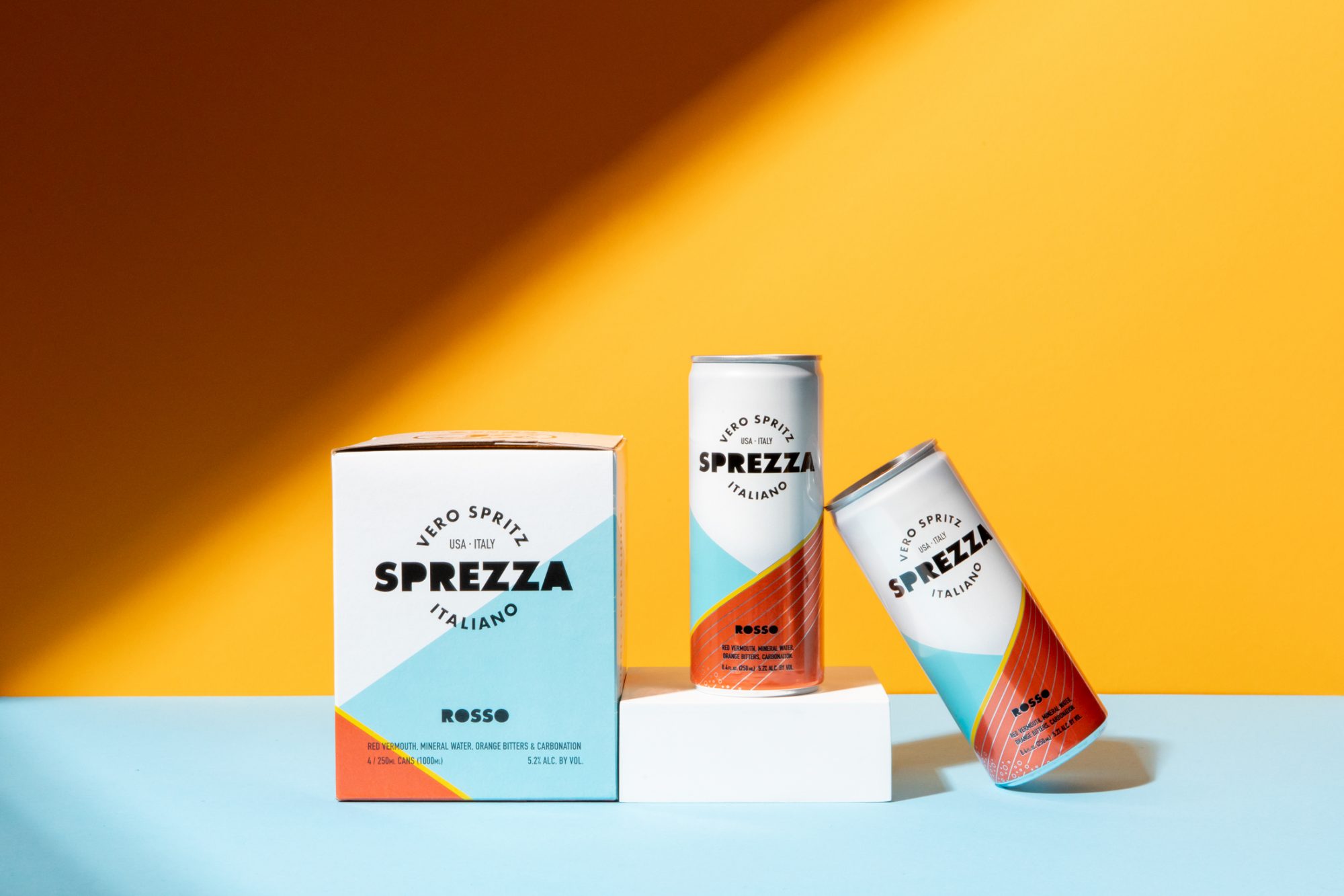 Seattle's best commercial food and hospitality photographer Two cans and a box of Sprezza Italian spritz are displayed against a yellow and blue background, styled by Seattles best commercial food lifestyle photographer. The colorful packaging features geometric designs and reads Vero Spritz Italiano Sprezza Rosso. captured by seattle's best food and lifestyle photographer Brooke Fitts