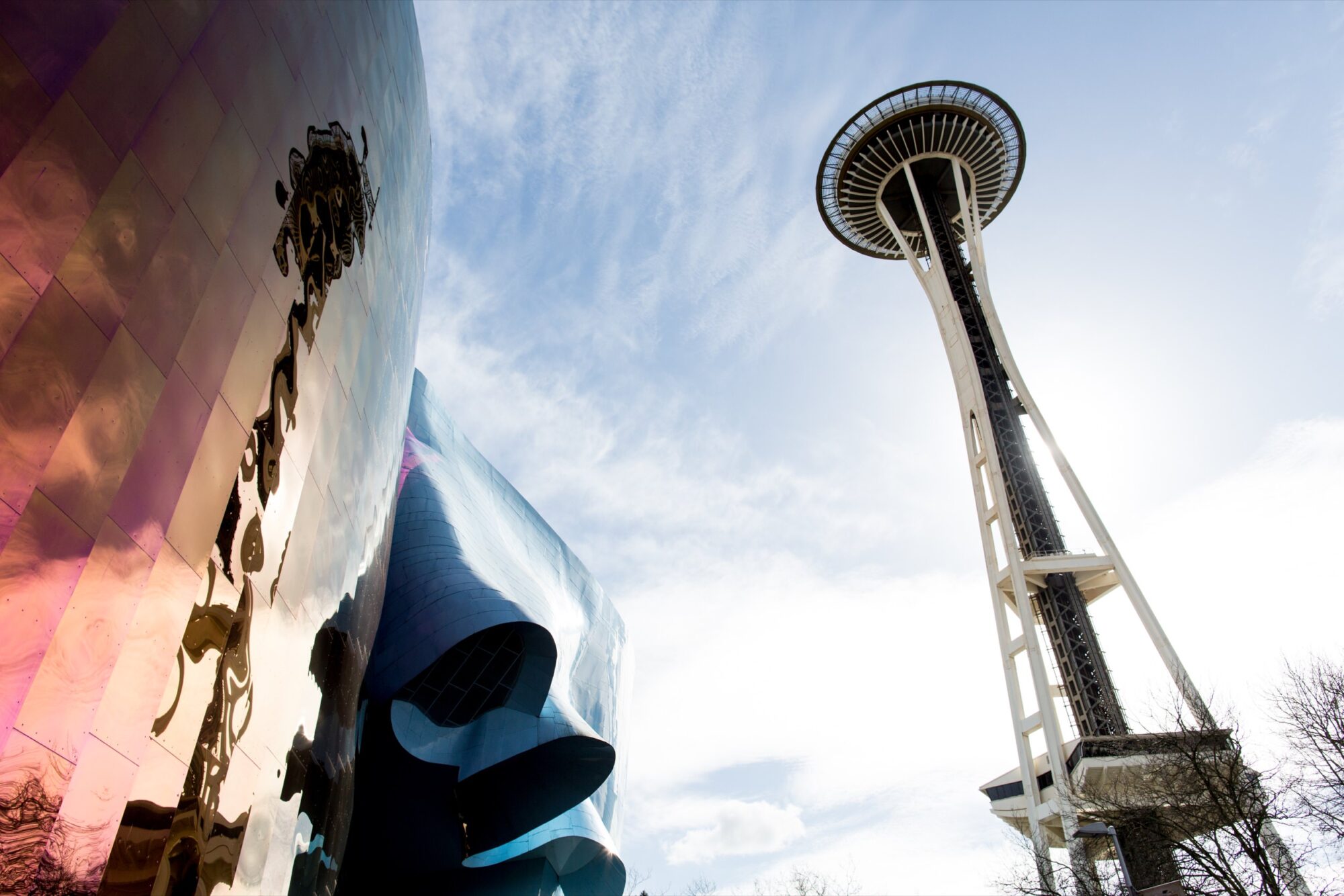 Seattle's best commercial food and hospitality photographer The Space Needle in Seattle towers against a blue sky, with the reflective, curved exterior of the Museum of Pop Culture on the left—captured through the lens of Seattles best commercial food lifestyle photographer. captured by seattle's best food and lifestyle photographer Brooke Fitts