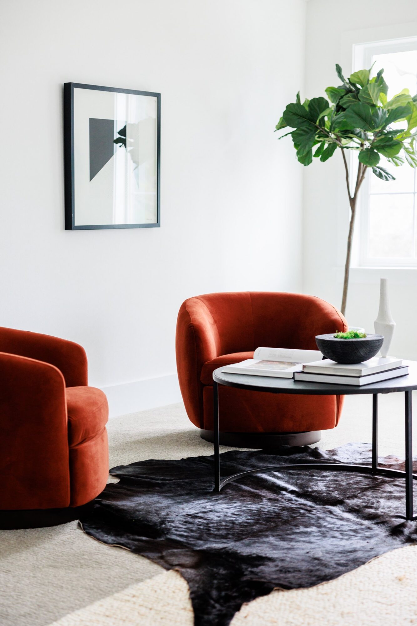 Seattle's best commercial food and hospitality photographer A modern living room with two orange velvet chairs, a round coffee table with books and a bowl, showcases the stylish touch of Seattles best commercial food lifestyle photographer, complemented by a black and white rug and abstract artwork. captured by seattle's best food and lifestyle photographer Brooke Fitts