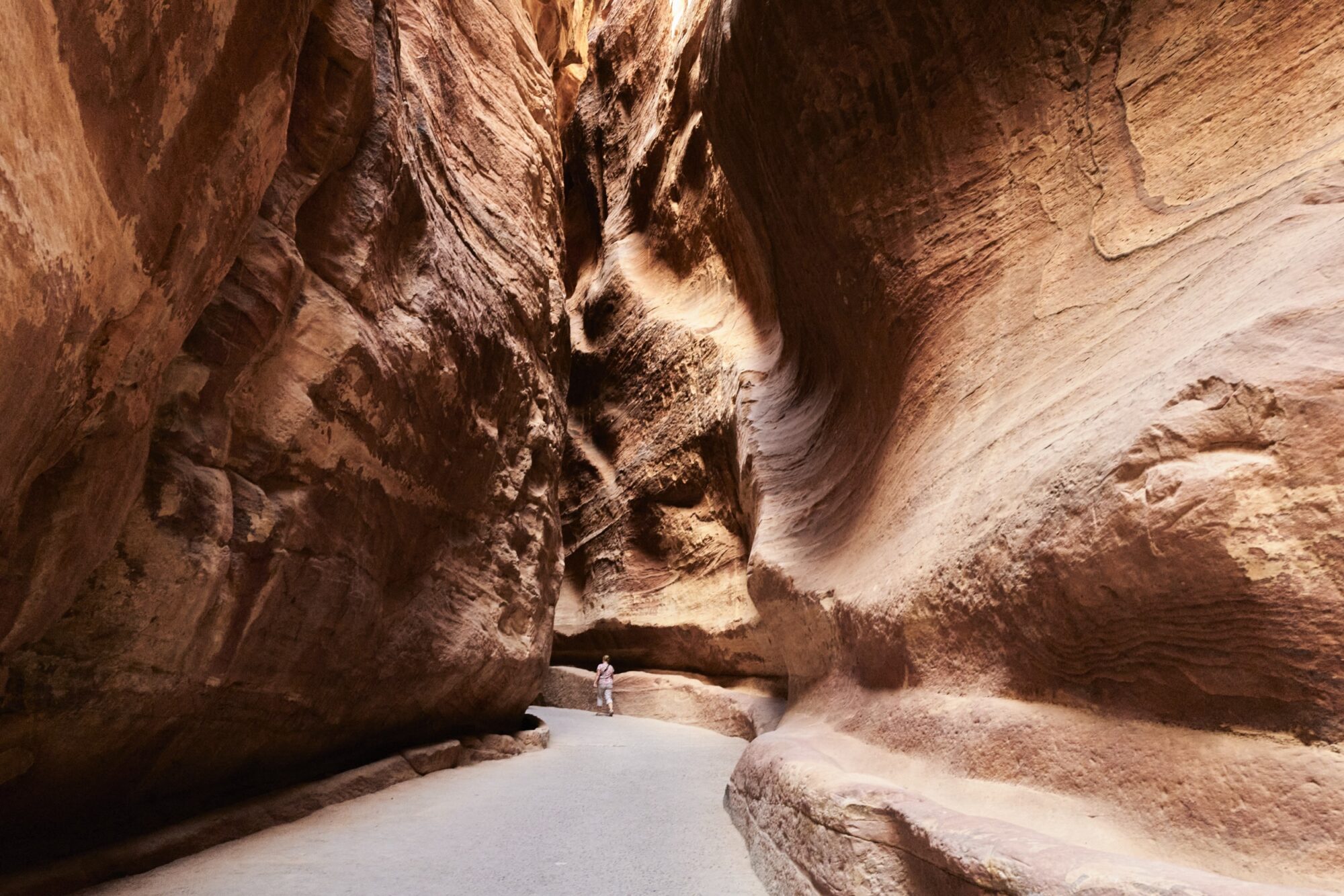 Seattle's best commercial food and hospitality photographer A person walks along a narrow, winding path between tall, smooth, reddish rock walls in a sunlit slot canyon, captured through the lens of Seattles best commercial food lifestyle photographer. captured by seattle's best food and lifestyle photographer Brooke Fitts