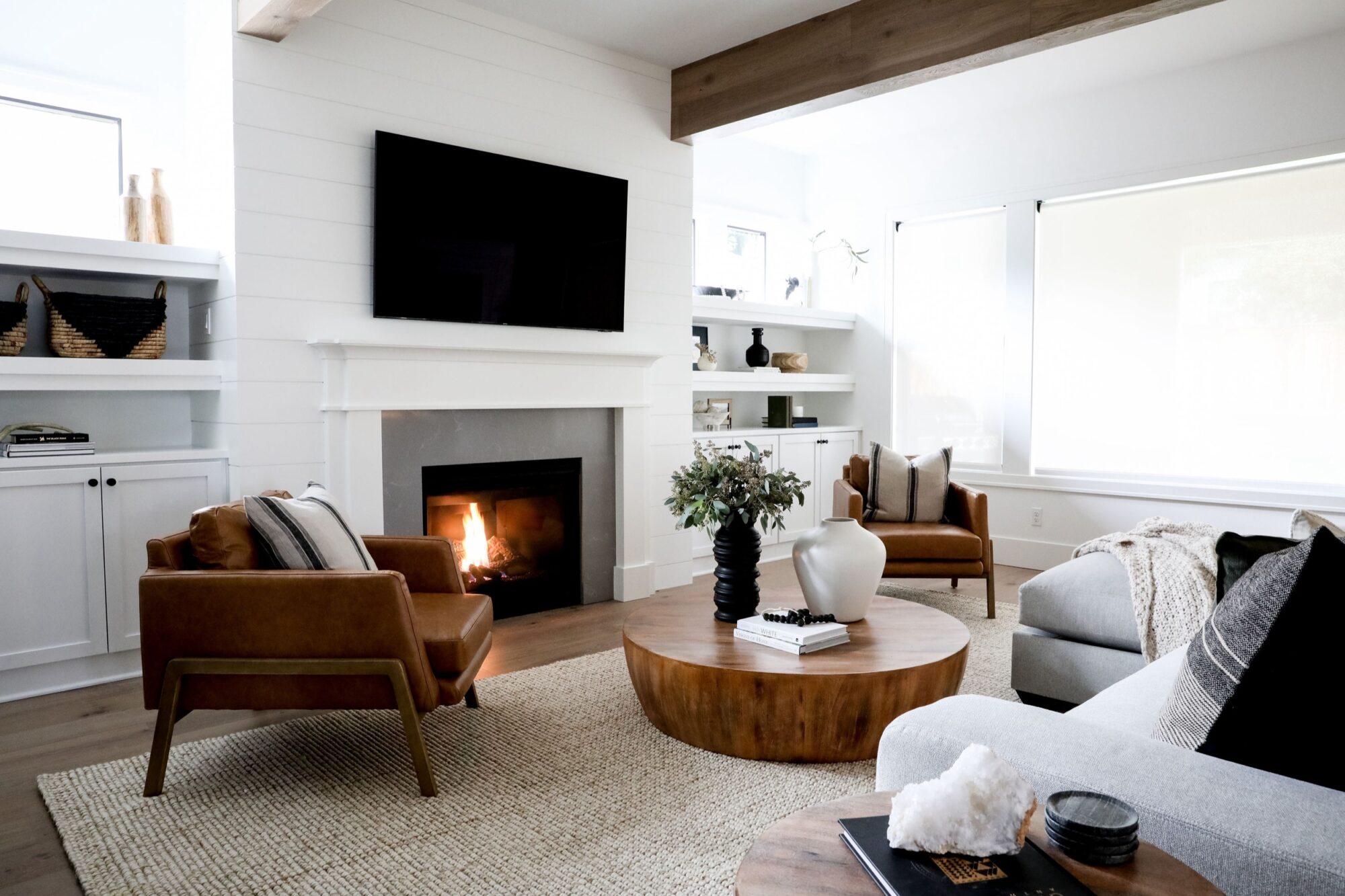 Seattle's best commercial food and hospitality photographer A modern living room with a lit fireplace, cozy seating, a round wooden coffee table, and natural light from large windows—styled and captured by Seattles best commercial food lifestyle photographer. captured by seattle's best food and lifestyle photographer Brooke Fitts