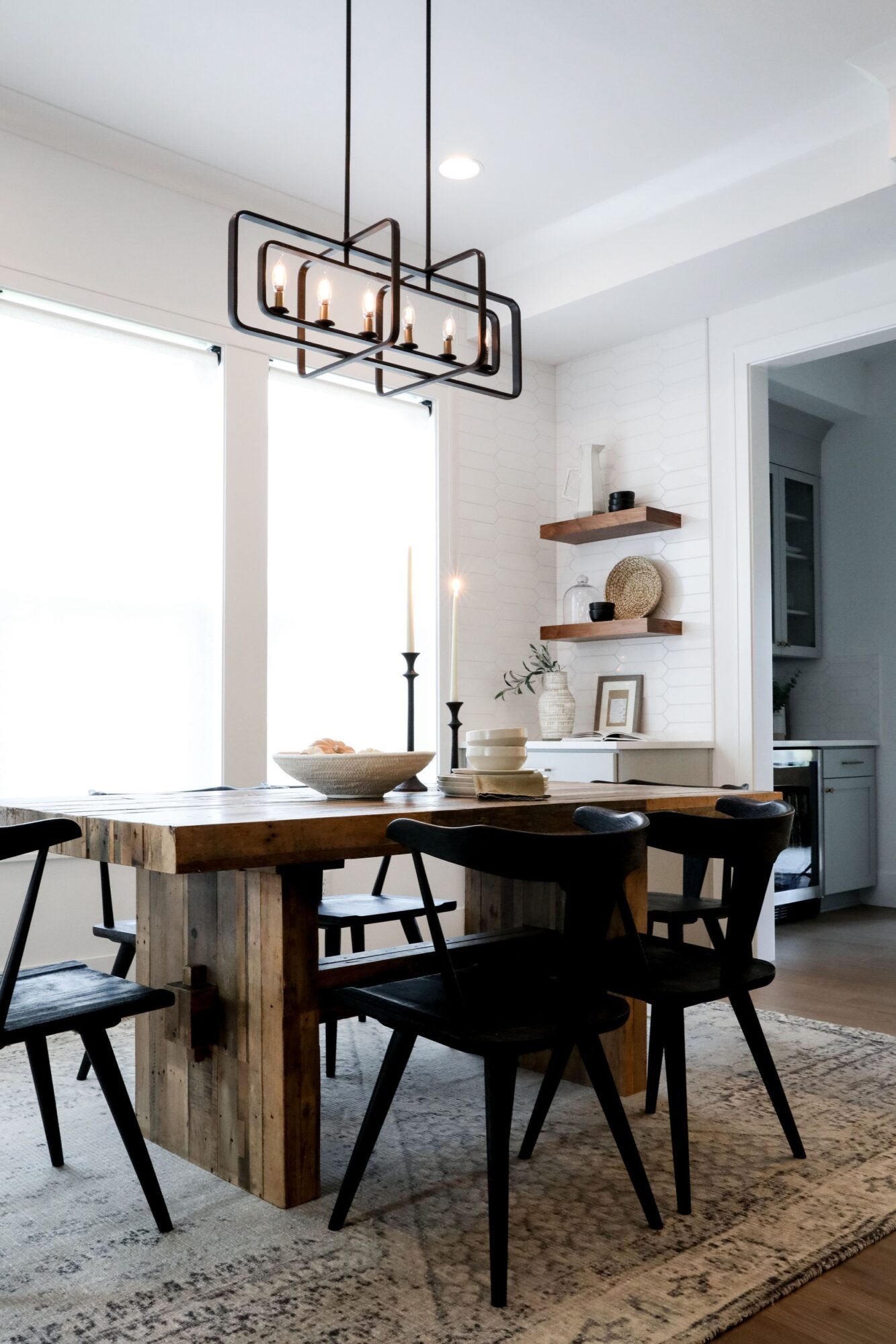 Seattle's best commercial food and hospitality photographer A modern dining room with a rustic wooden table, black chairs, and a geometric chandelier is perfectly captured by Seattles best commercial food lifestyle photographer—highlighting the textured rug and decor-filled shelves bathed in natural light. captured by seattle's best food and lifestyle photographer Brooke Fitts