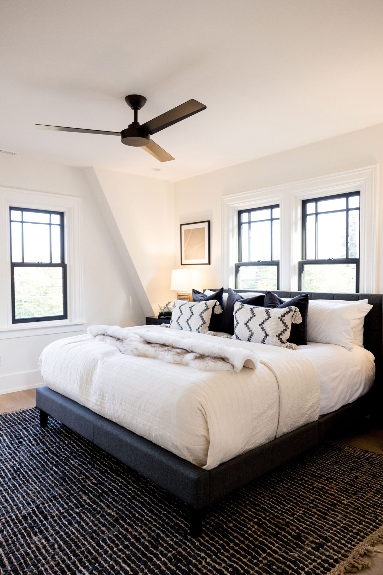 Seattle's best commercial food and hospitality photographer A modern bedroom with a large bed, black and white pillows, a textured black rug, light walls, two windows with black frames—styled like Seattles best commercial food lifestyle photographer would capture it. captured by seattle's best food and lifestyle photographer Brooke Fitts
