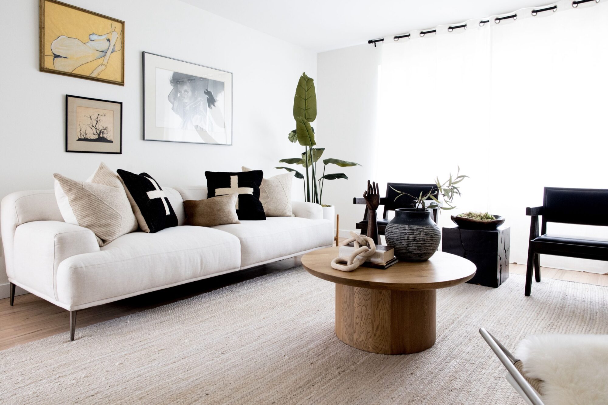 Seattle's best commercial food and hospitality photographer A modern, minimalist living room with a white sofa, neutral-toned pillows, a round wooden coffee table, and sunlight streaming in—captured by Seattles best commercial food lifestyle photographer. captured by seattle's best food and lifestyle photographer Brooke Fitts