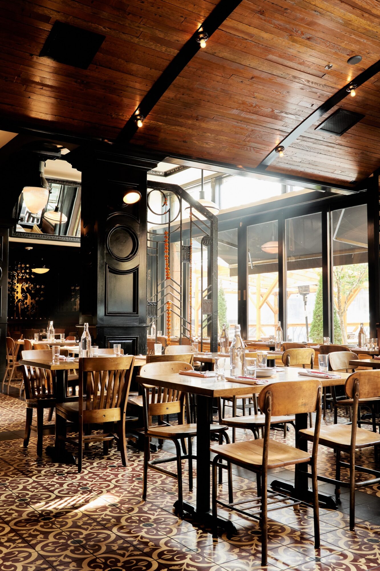 Seattle's best commercial food and hospitality photographer A stylish restaurant interior captured by Seattles best commercial food lifestyle photographer, featuring wooden tables and chairs, patterned tile flooring, and large windows. Dark wood accents create a warm and inviting atmosphere. captured by seattle's best food and lifestyle photographer Brooke Fitts