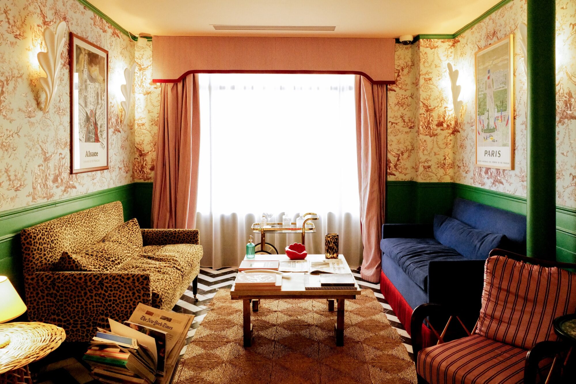 Seattle's best commercial food and hospitality photographer A cozy living room with patterned wallpaper, a leopard-print sofa, a blue couch, and a striped chair. Sunlight streams through large curtained windows—captured beautifully by Seattles best commercial food lifestyle photographer. captured by seattle's best food and lifestyle photographer Brooke Fitts