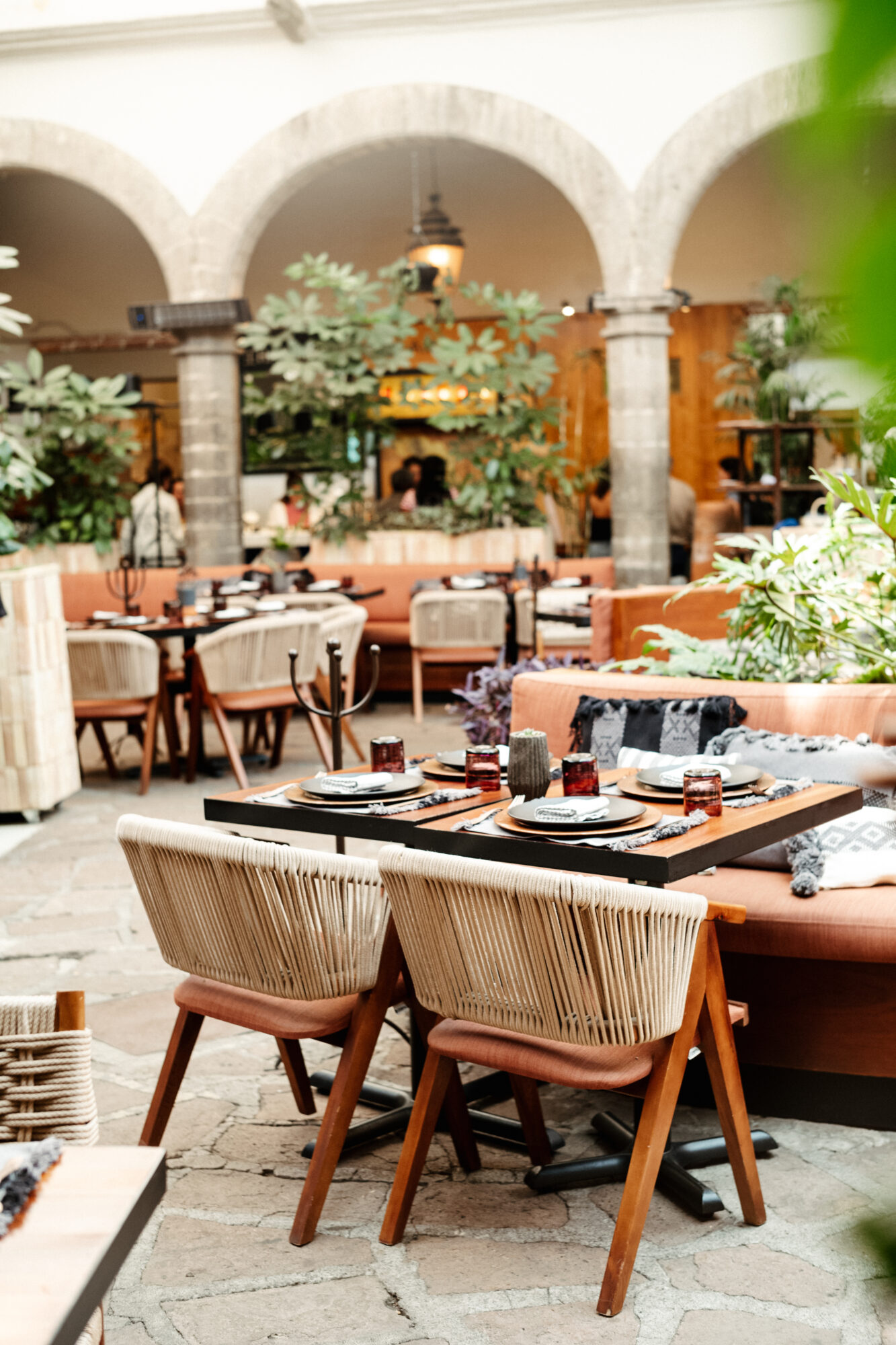 Seattle's best commercial food and hospitality photographer An elegant outdoor restaurant patio with arched stone columns, wooden tables set for dining, cushioned chairs, and lush green plants—beautifully captured by Seattles best commercial food lifestyle photographer. captured by seattle's best food and lifestyle photographer Brooke Fitts