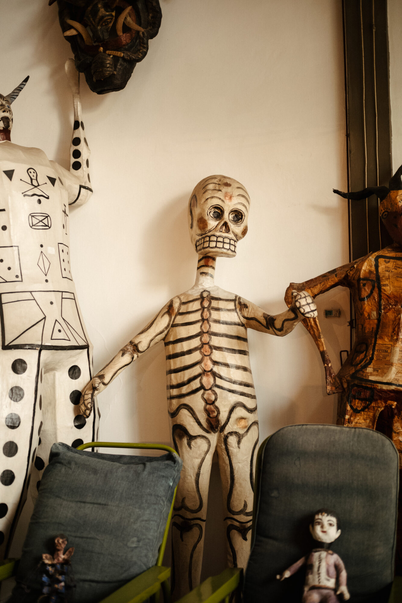 Seattle's best commercial food and hospitality photographer A tall skeleton figure with painted bones stands indoors between two other large, stylized figures. In front, two gray chairs with small dolls add to the eclectic, artistic scene—captured by Seattles best commercial food lifestyle photographer. captured by seattle's best food and lifestyle photographer Brooke Fitts