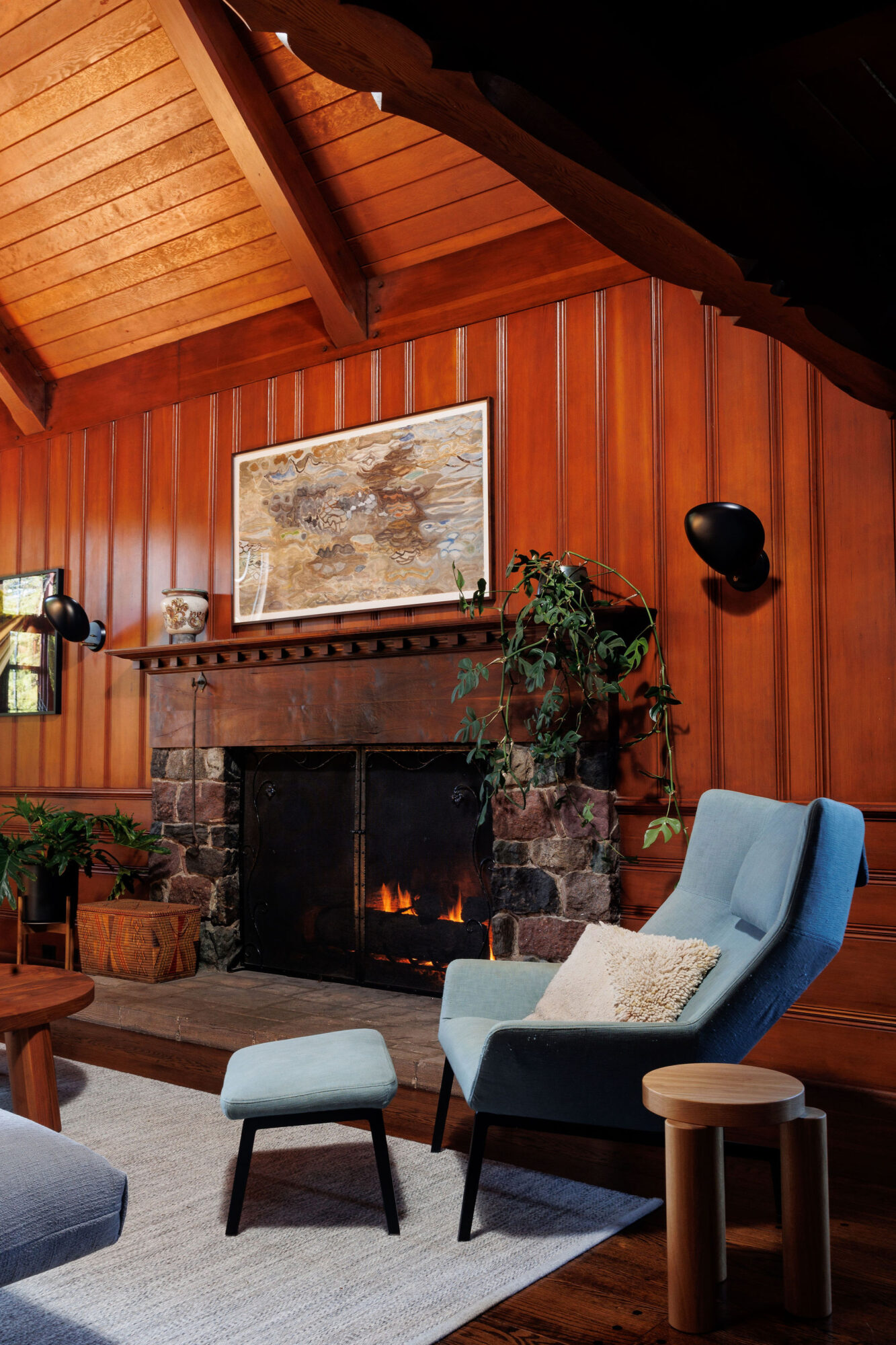 Seattle's best commercial food and hospitality photographer A cozy living room with wood-paneled walls, a stone fireplace with a fire burning, and warm lighting creating a comfortable atmosphere—captured perfectly by Seattles best commercial food lifestyle photographer. captured by seattle's best food and lifestyle photographer Brooke Fitts