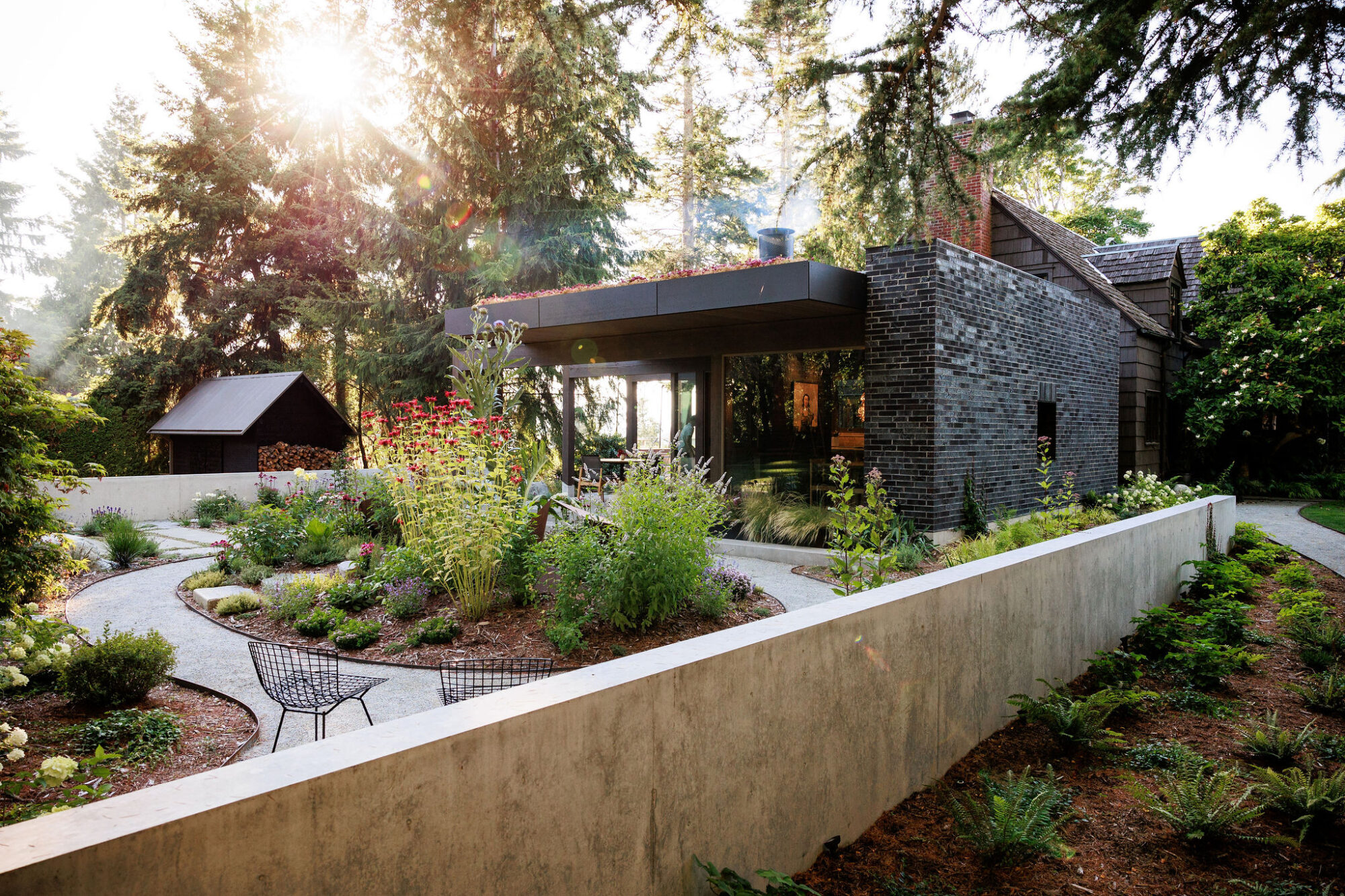 Seattle's best commercial food and hospitality photographer Modern brick house with large windows, lush gardens, and a curved pathway—captured in the style of Seattles best commercial food lifestyle photographer. Sunlight highlights vibrant landscaping and an inviting outdoor seating area. captured by seattle's best food and lifestyle photographer Brooke Fitts