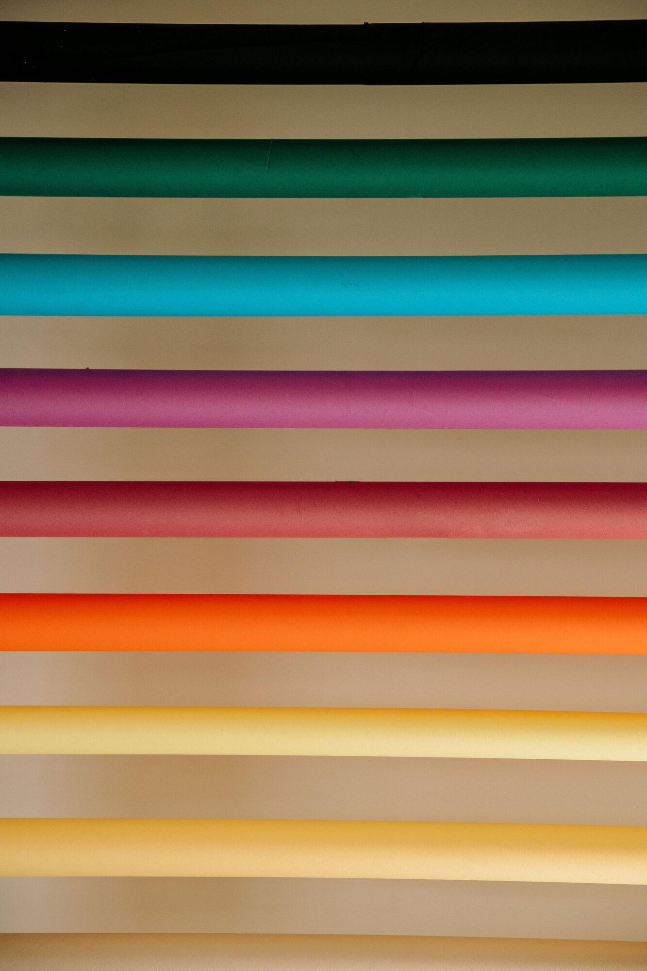 Seattle's best commercial food and hospitality photographer Rows of colorful horizontal pipes or tubes in black, green, blue, teal, purple, pink, red, orange, yellow, and beige are mounted against a neutral background—captured by Seattles best commercial food lifestyle photographer. captured by seattle's best food and lifestyle photographer Brooke Fitts