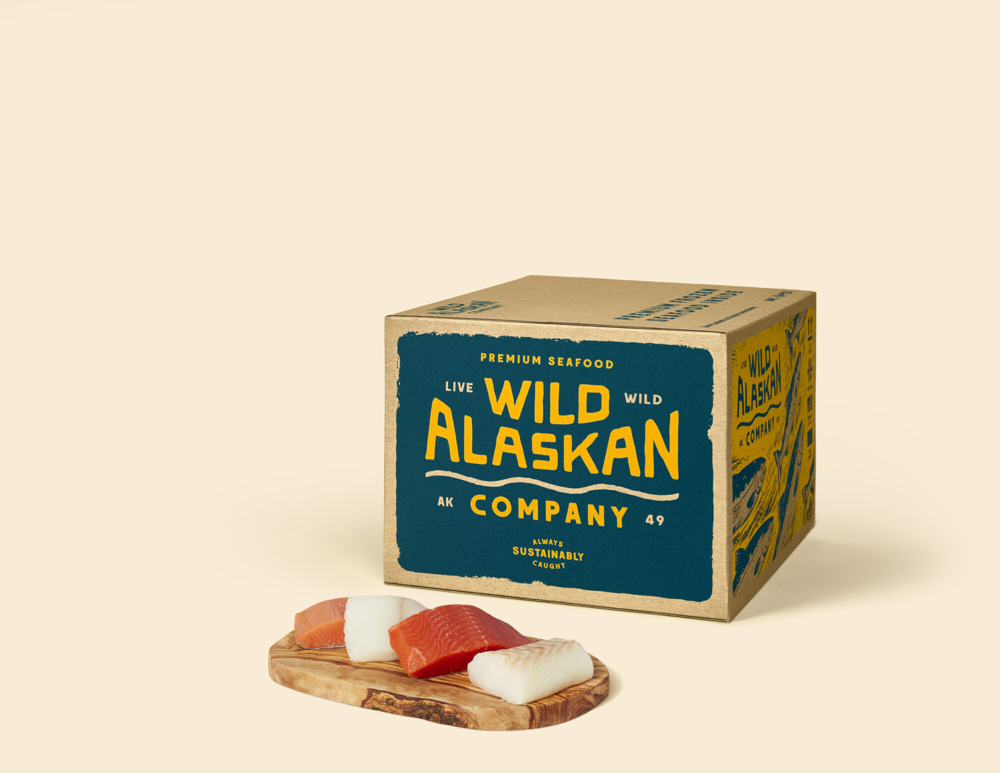 Seattle's best commercial food and hospitality photographer A box labeled Wild Alaskan Company with bold yellow text sits on a light surface. In front, three pieces of sashimi-style raw fish rest on a small wooden board—captured by Seattles best commercial food lifestyle photographer. The background is plain beige. captured by seattle's best food and lifestyle photographer Brooke Fitts