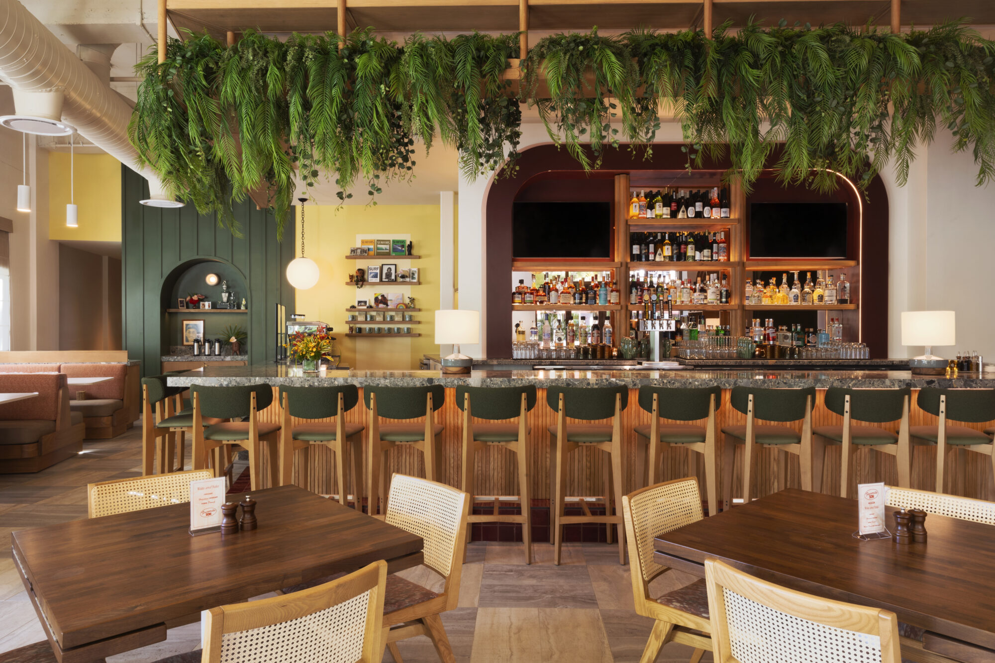 Elegant bar interior design showcasing a stylish counter with stocked shelves and greenery in a contemporary setting