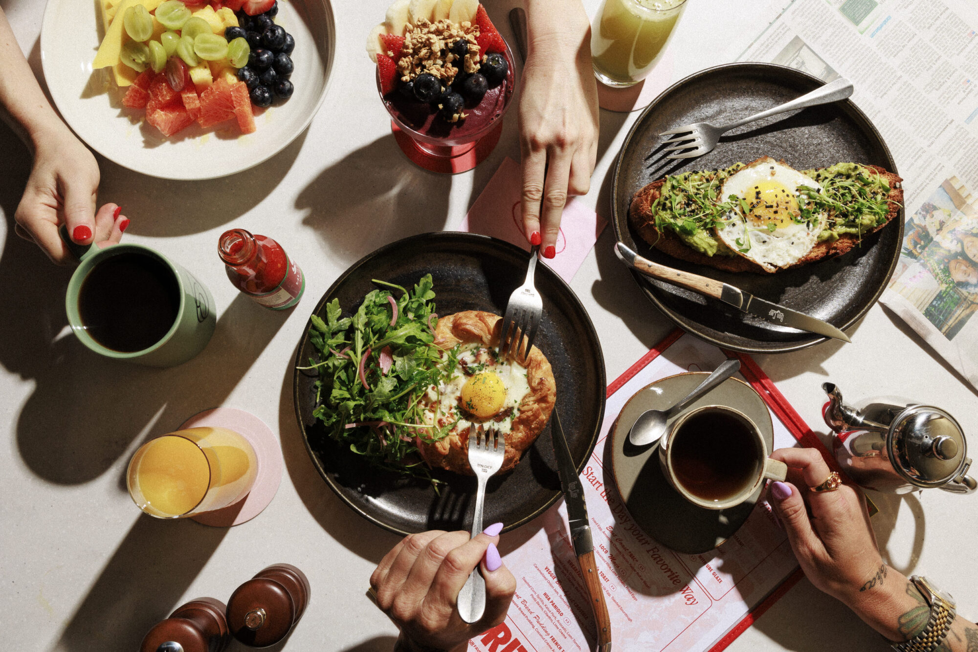 Group of friends enjoying brunch with assorted dishes at a vibrant cafe on a sunny morning