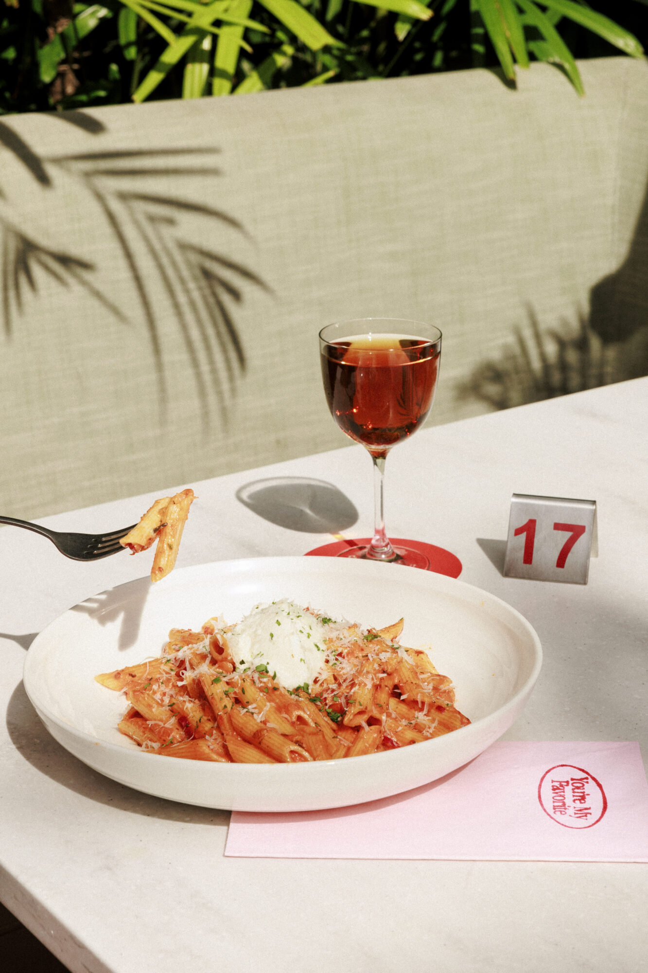 Delicious pasta dish served with a drink in a warm outdoor setting at a lively restaurant table