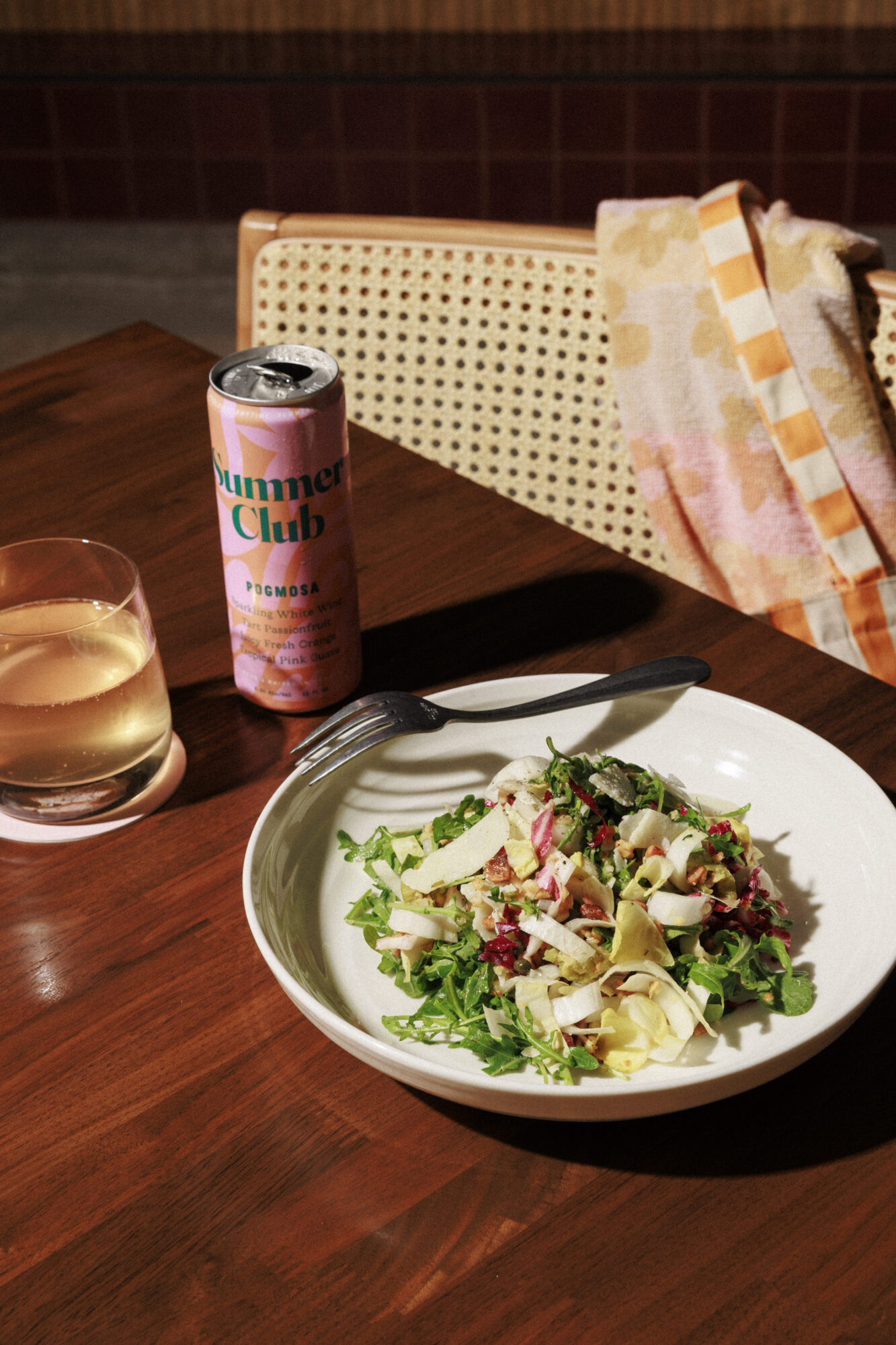 Fresh salad served with a sparkling beverage on a wooden table in a cozy setting
