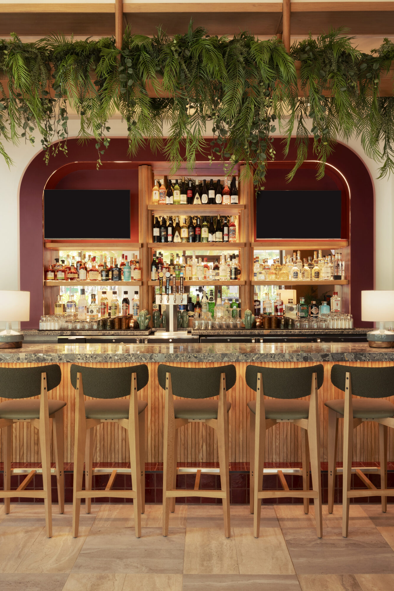 Elegant bar interior design showcasing a stylish counter with stocked shelves and greenery in a contemporary setting