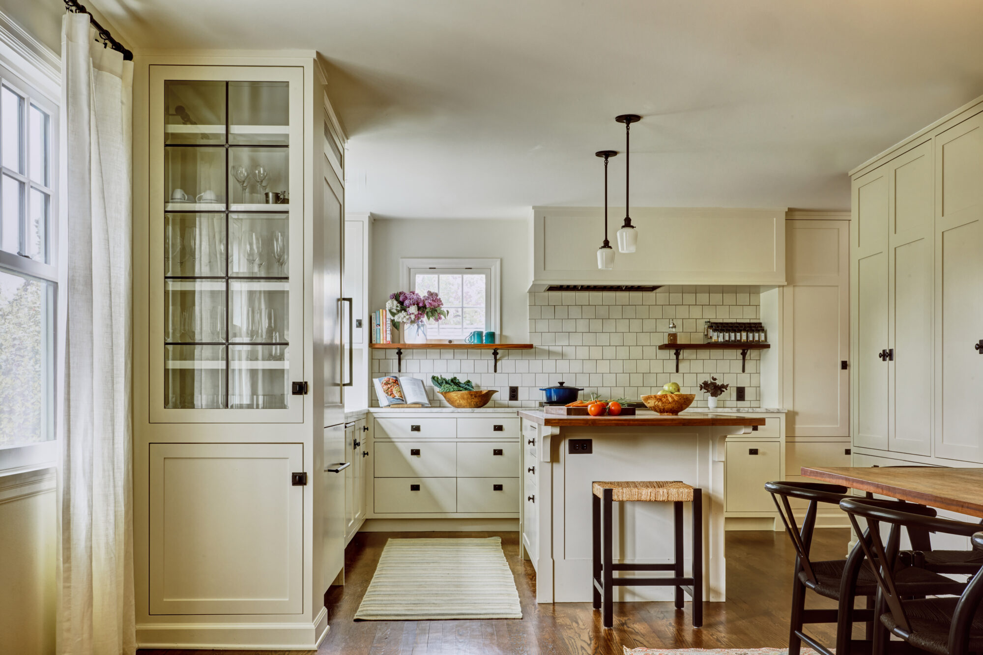 Seattle's best commercial food and hospitality photographer Bright, modern kitchen with cream cabinets, subway tile backsplash, wooden island with stools, and abundant natural light—captured by a Seattle commercial interior design photographer for restaurants and hotels. Open shelves showcase stylish dishes and decor. captured by seattle's best food and lifestyle photographer Brooke Fitts