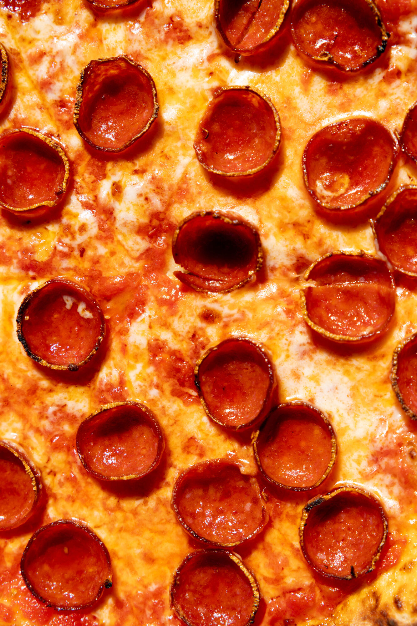 Close-up of a pepperoni pizza, showing melted cheese and evenly spaced, crispy-edged pepperoni slices on a golden crust. captured by seattle's best food and hospitality photographer Brooke Fitts
